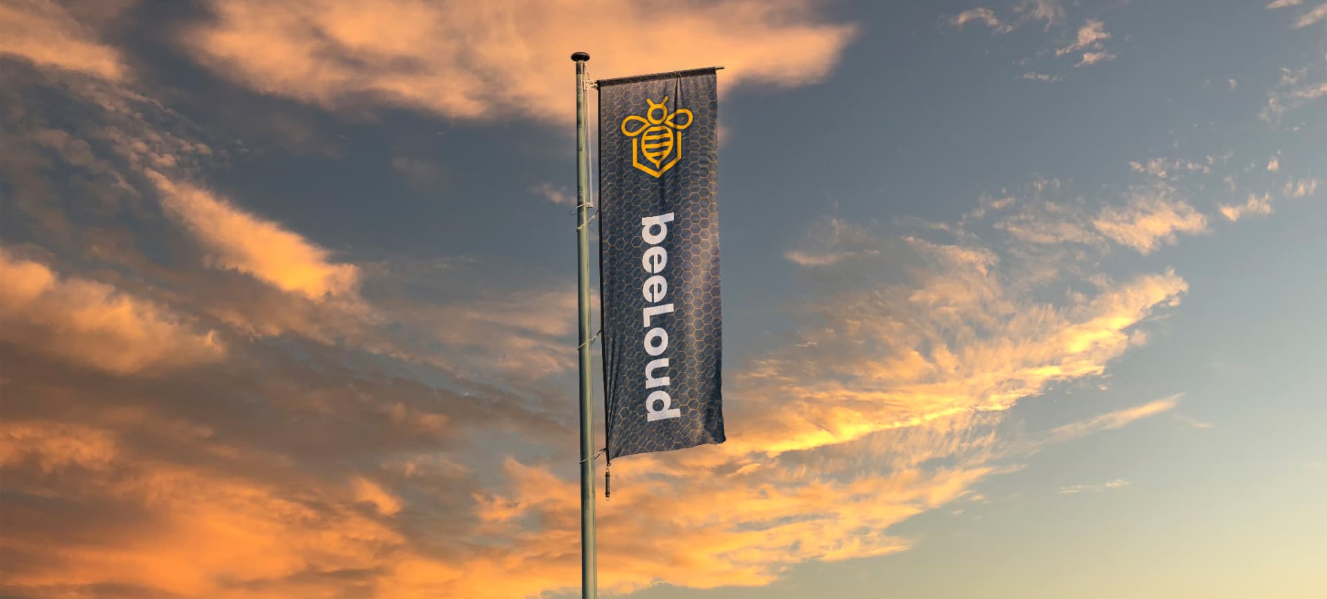 De beeLoud-vlag tegen een oranje avondlucht boven Texel