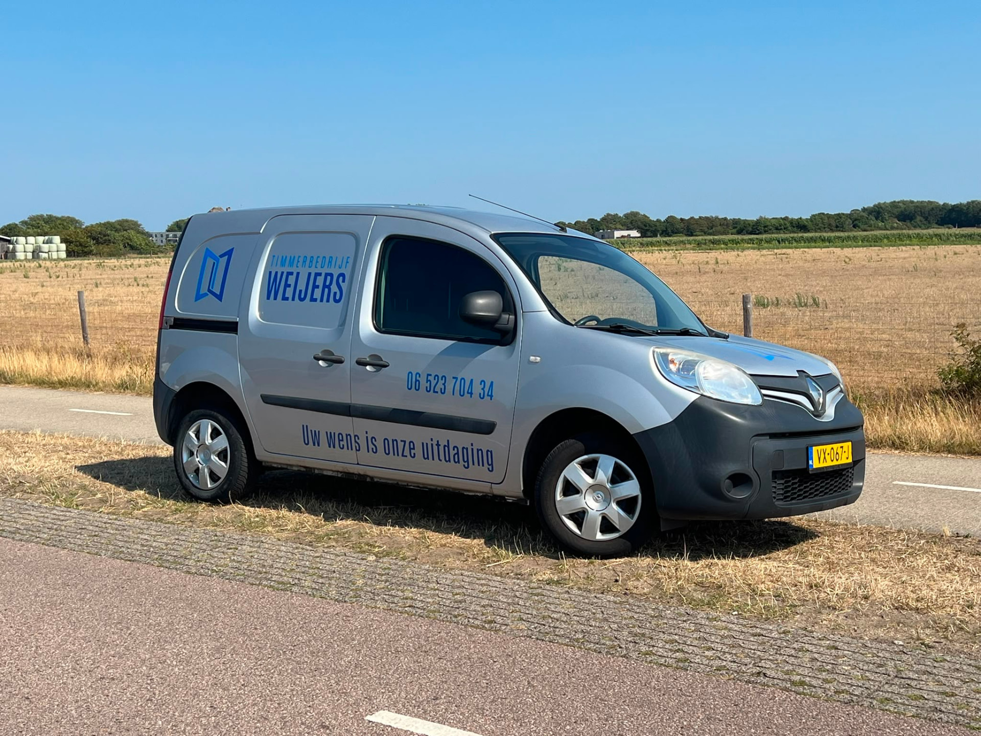 Bedrijfsbus van Timmerbedrijf Weijers met blauwe belettering op Texel