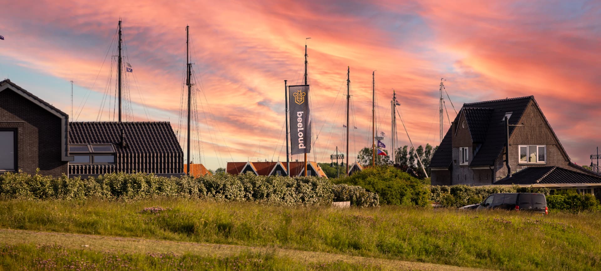 Zonsondergang boven de haven van Oudeschild met de beeLoud-vlag tussen de masten