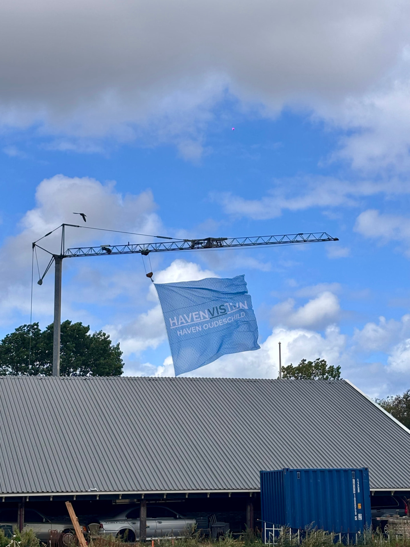 Vlag van HavenVIStijn van 6 bij 6 meter aan een kraan op het terrein in Oudeschild
